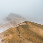 Imagem de homem trilhando um caminho em meio a montanhas simbolizando coerência